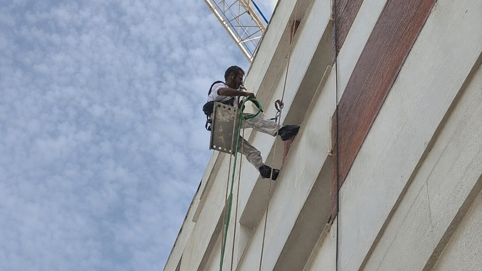 Pintor de Pinturas Pizarro pintando la fachada de un edificio mediante trabajos verticales