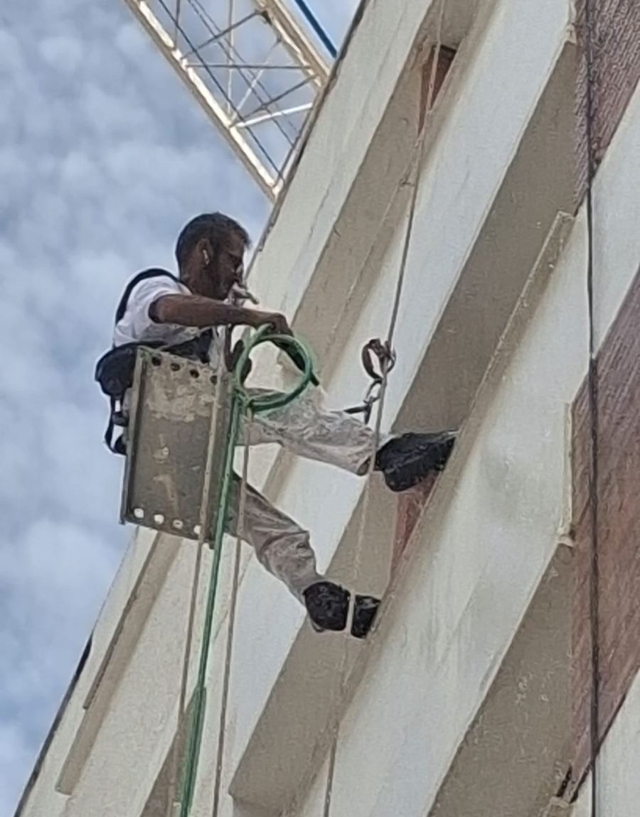 Técnico de Pinturas Pizarro descolgado con cuerdas pintando una fachada
